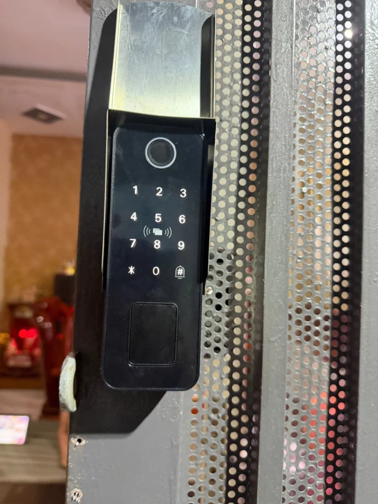 Cụm khóa vân tay và bàn phím đặt trong hộp inox trên cổng lưới