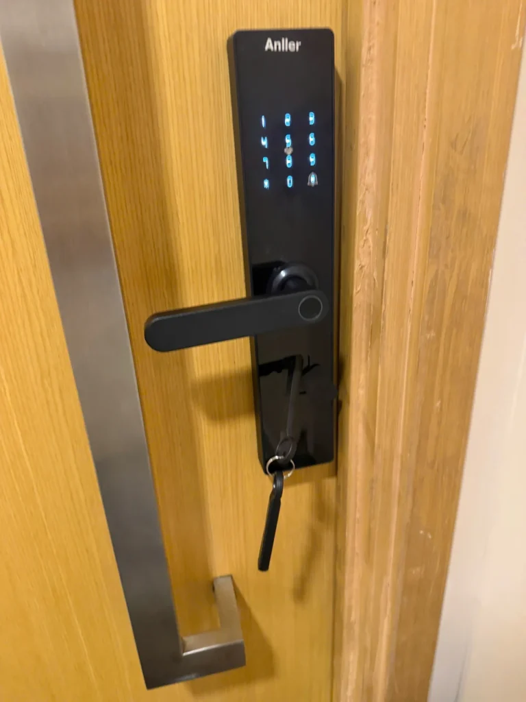 Khóa vân tay Anller trên cửa gỗ có tay nắm kéo inox, chìa cơ cắm ở ổ dự phòng