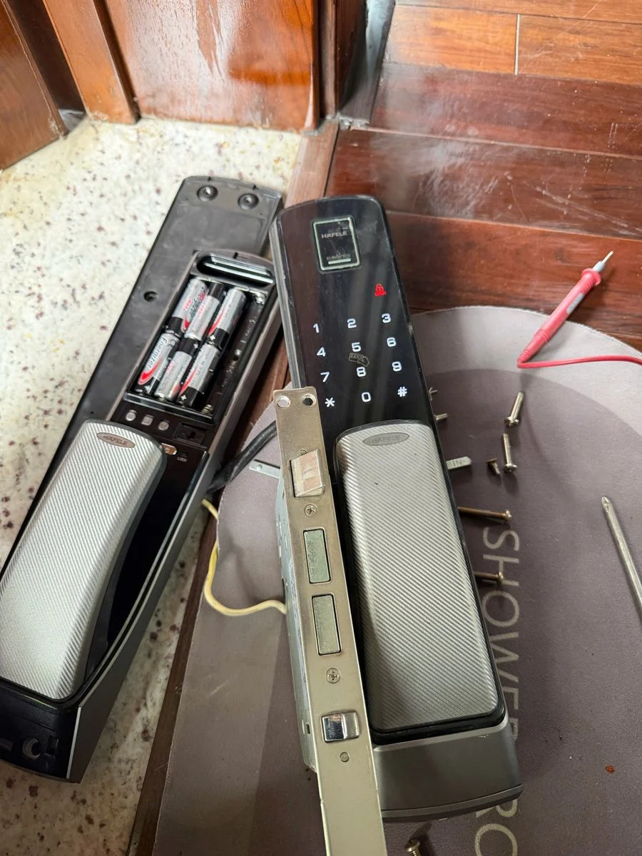 Khóa Hafele tháo rời, khoang pin mở, thân khóa đặt cạnh và que đo đồng hồ vạn năng